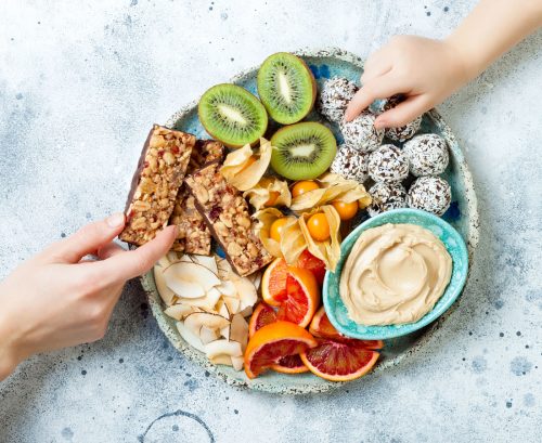 two hand reaching for an array of healthy snacks on a plate