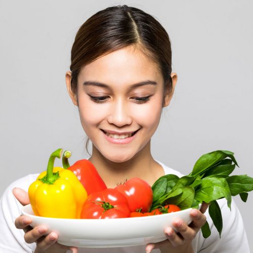 Teenage girl smiling at a plate of vegetables
